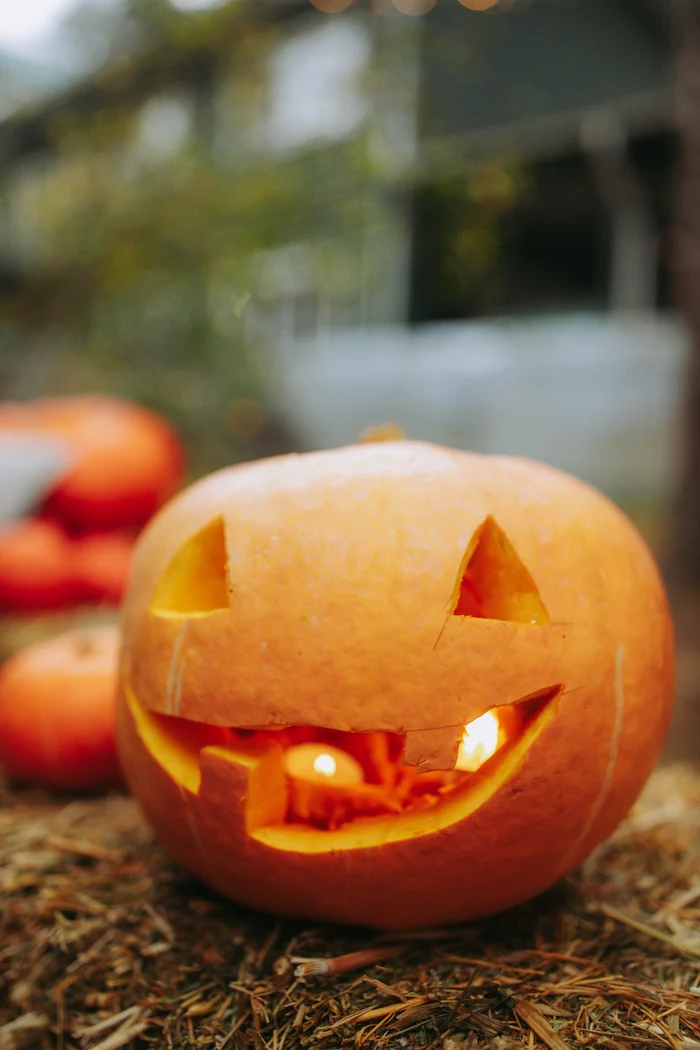 わらの上に置かれた、笑顔のハロウィンかぼちゃ